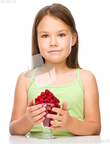 Image of Happy little girl is eating raspberries