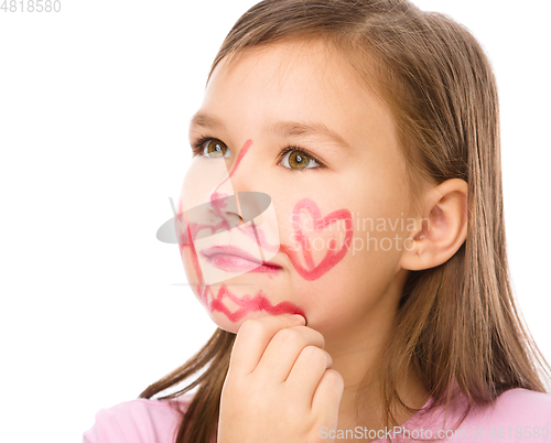 Image of Little girl is applying lipstick on her cheek