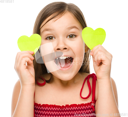 Image of Little girl is holding hearts near her eyes