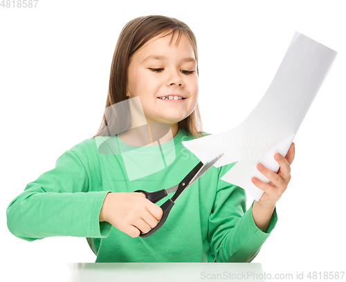 Image of Little girl is cutting paper using scissors