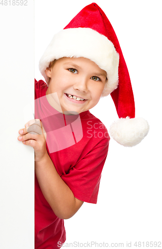 Image of Little girl in santa hat is holding blank board