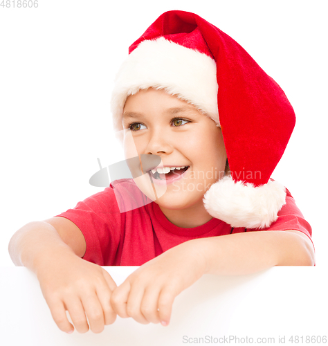 Image of Little girl in santa hat is holding blank board