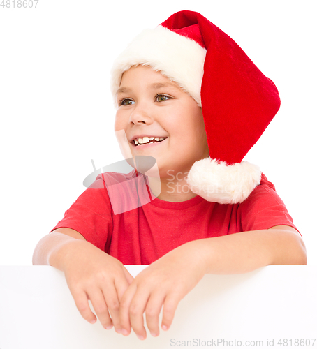 Image of Little girl in santa hat is holding blank board