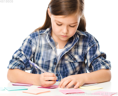 Image of Girl is writing on color stickers using pen