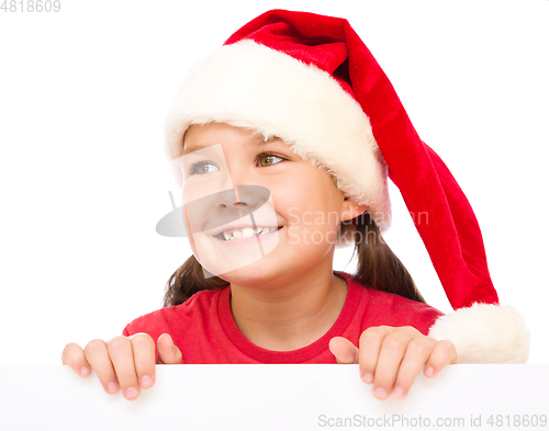 Image of Little girl in santa hat is holding blank board