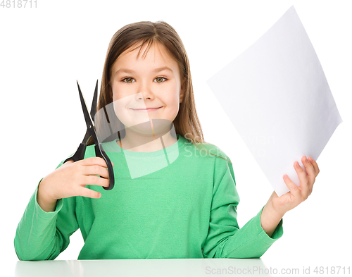 Image of Little girl is cutting paper using scissors