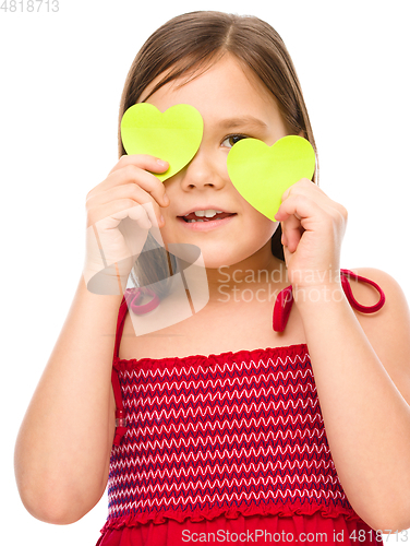 Image of Little girl is holding hearts over her eyes