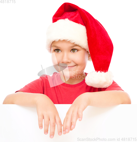 Image of Little girl in santa hat is holding blank board