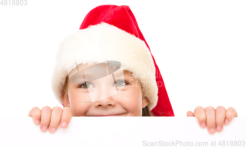 Image of Little girl in santa hat is holding blank board