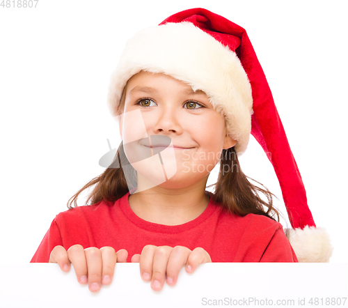 Image of Little girl in santa hat is holding blank board