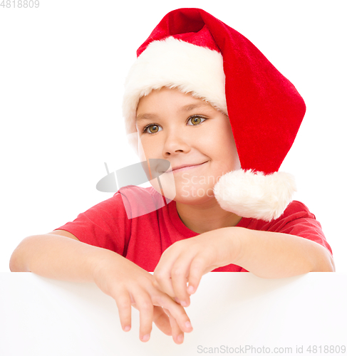 Image of Little girl in santa hat is holding blank board