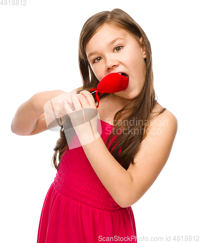Image of Portrait of a little girl biting red heart