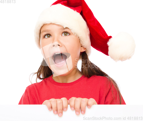 Image of Little girl in santa hat is holding blank board