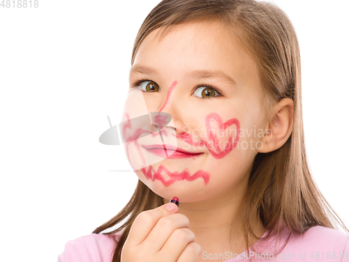 Image of Little girl is applying lipstick on her cheek