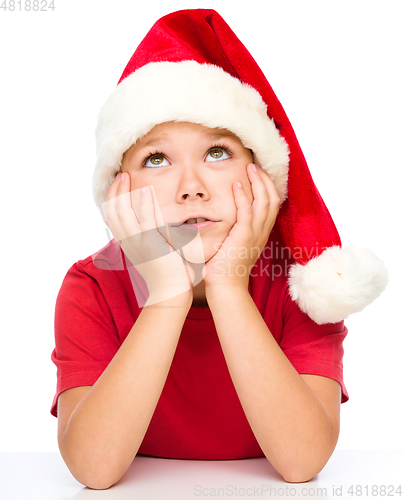Image of Little girl in santa hat is daydreaming