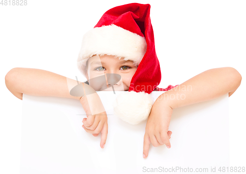 Image of Little girl in santa hat is holding blank board