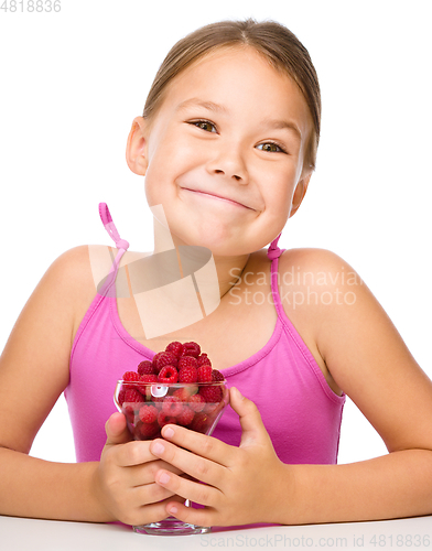 Image of Happy little girl is eating raspberries