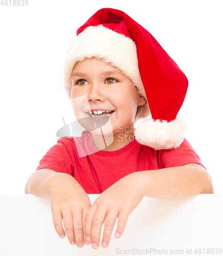 Image of Little girl in santa hat is holding blank board
