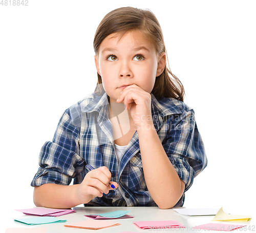 Image of Girl is writing on color stickers using pen