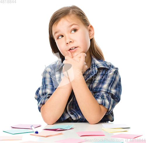 Image of Girl is writing on color stickers using pen