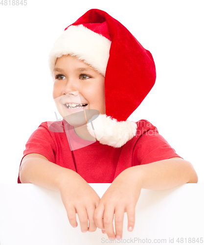 Image of Little girl in santa hat is holding blank board