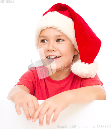 Image of Little girl in santa hat is holding blank board