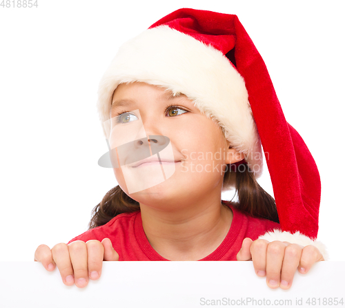 Image of Little girl in santa hat is holding blank board