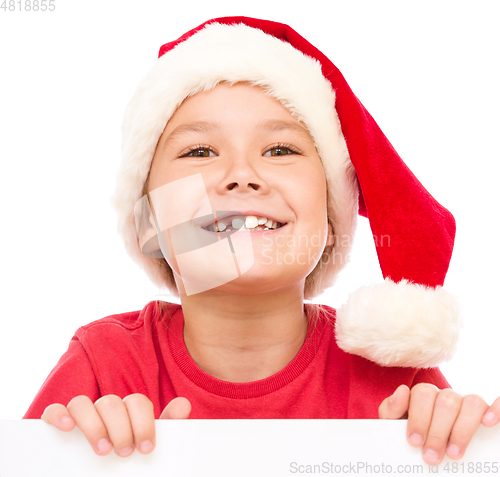 Image of Little girl in santa hat is holding blank board