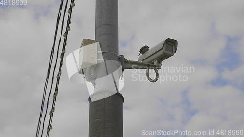 Image of Bird sits on CCTV camera on high pillar.