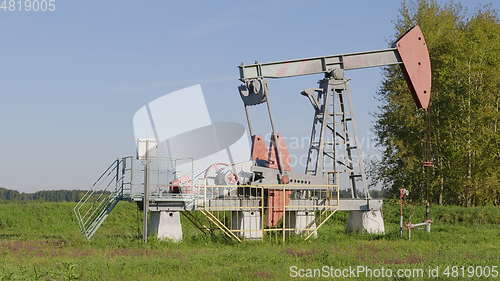 Image of Operating oil and gas well in oil field, profiled against the blue sky