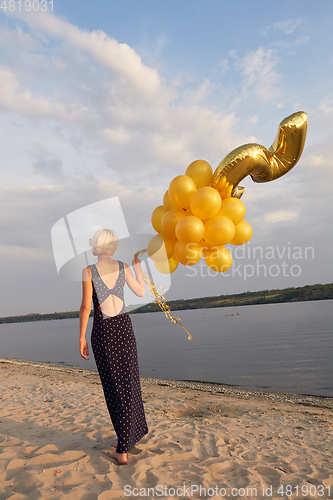 Image of Young woman with many golden balloons.