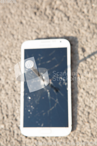 Image of metal nail and smartphone with a broken screen over the stone surface. The concept of strength.