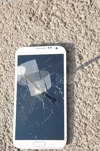 Image of metal nail and smartphone with a broken screen over the stone surface. The concept of strength.