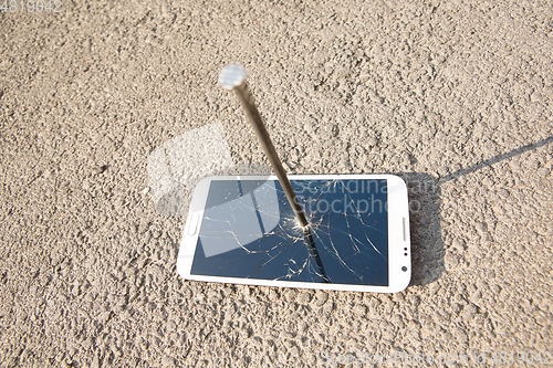 Image of metal nail and smartphone with a broken screen over the stone surface. The concept of strength.