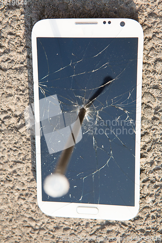 Image of metal nail and smartphone with a broken screen over the stone surface. The concept of strength.