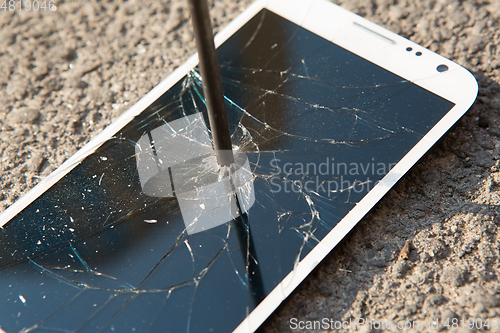 Image of metal nail and smartphone with a broken screen over the stone surface. The concept of strength.