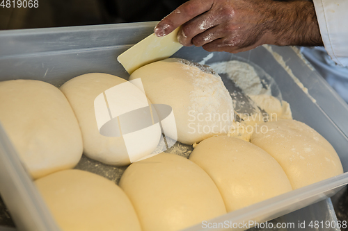 Image of Small balls of fresh homemade pizza dough on floured wooden boar