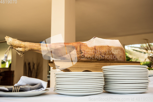 Image of Chef slices serrano ham. Jamon Serrano. Typical Spanish delicatessen prosciutto.