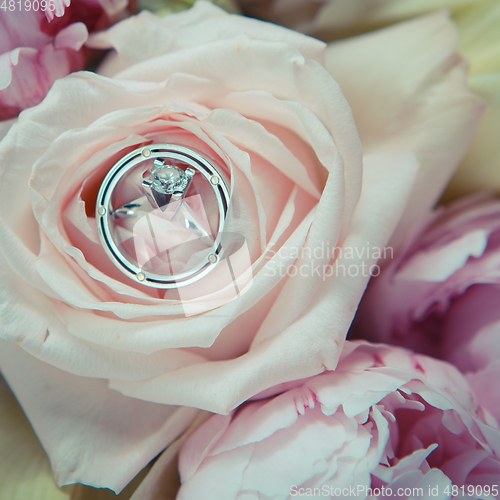 Image of wedding rings lie on a beautiful bouquet as bridal accessories