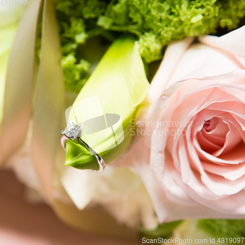 Image of wedding rings lie on a beautiful bouquet as bridal accessories.