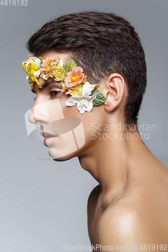 Image of handsome young man with flowers on face