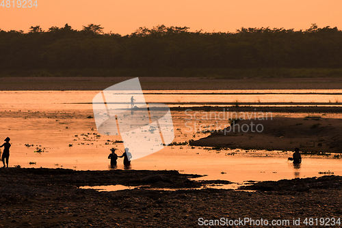 Image of Asian women fishing in the river, silhouette at sunset