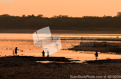 Image of Asian women fishing in the river, silhouette at sunset