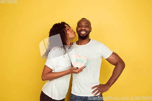 Image of Valentine\'s day celebration, happy african-american couple isolated on yellow background