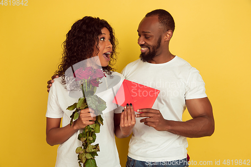 Image of Valentine\'s day celebration, happy african-american couple isolated on yellow background