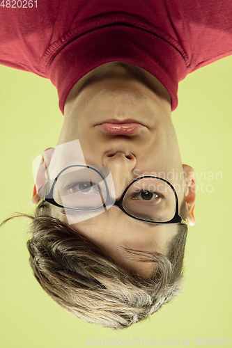 Image of Inverted portrait of caucasian young man on yellow studio background