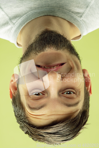 Image of Inverted portrait of caucasian young man on yellow studio background