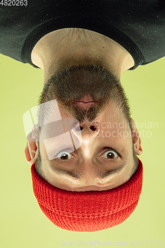 Image of Inverted portrait of caucasian young man on yellow studio background