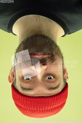 Image of Inverted portrait of caucasian young man on yellow studio background