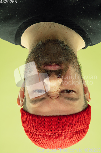 Image of Inverted portrait of caucasian young man on yellow studio background